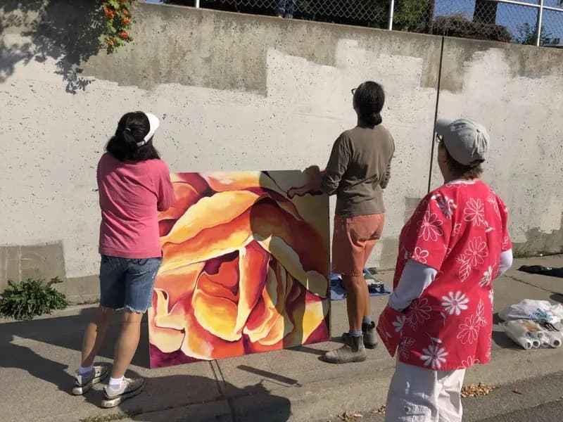 Volunteers installing flower painting on the hillside wall